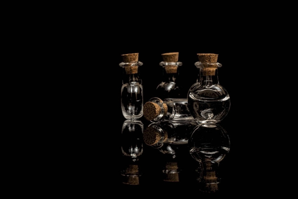 Glass empty flasks with corks on a black background. Isolate on black. - Photo, Image