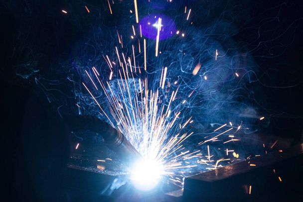 The process of welding metal in the dark with the formation of a large amount of smoke and sparks. - Photo, Image