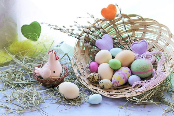 Happy Easter, a basket with painted eggs, a toy chicken, hay on the windowsill, interior decor for the holiday - Photo, Image