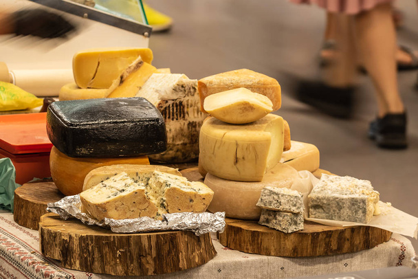 Gasztronómiai svédasztalos, különböző típusú sajtok bemutatásával, amelyeket fapadlókon mutatnak be. Konyha a szabadban. Utcai vásárcsarnok. - Fotó, kép