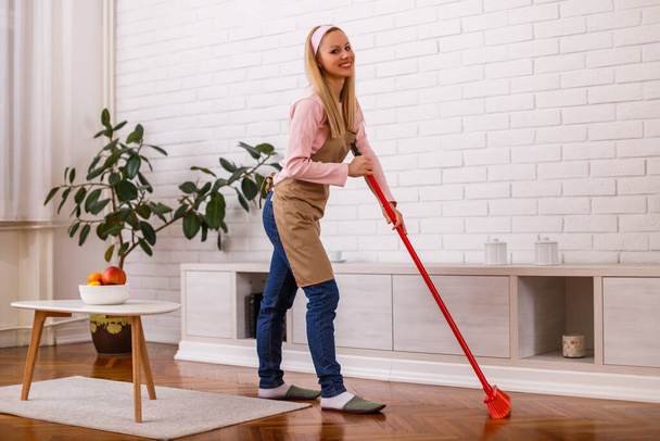 Beautiful housewife cleaning with broom her home. - Foto, Imagem