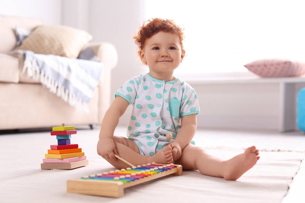 Cute little child playing with xylophone on floor at home - Foto, Imagem