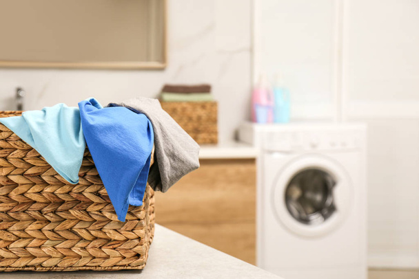 Wicker basket with laundry on countertop in bathroom, closeup. Space for text - Zdjęcie, obraz