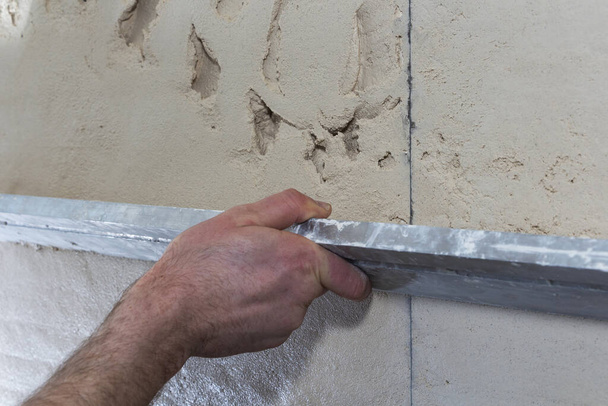 Travailleur de la construction avec une longue spatule pour plâtrer le mur à la main
 - Photo, image