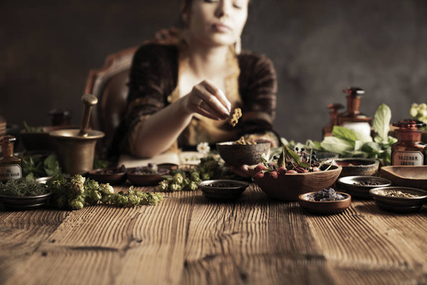 Natural medicine concept. Vintage pharmacist preparing natural medicament. Brass mortar and  bottles. Rustic table. Assorted dry herbs in bowls. - 写真・画像