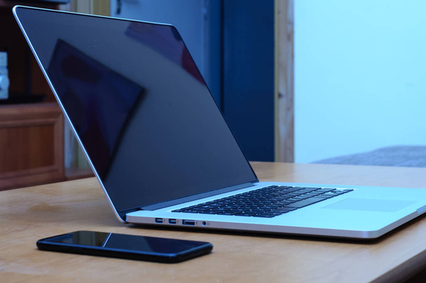 Вид на ноутбук и смартфон на столе в домашнем офисе в гостиной
. - Фото, изображение