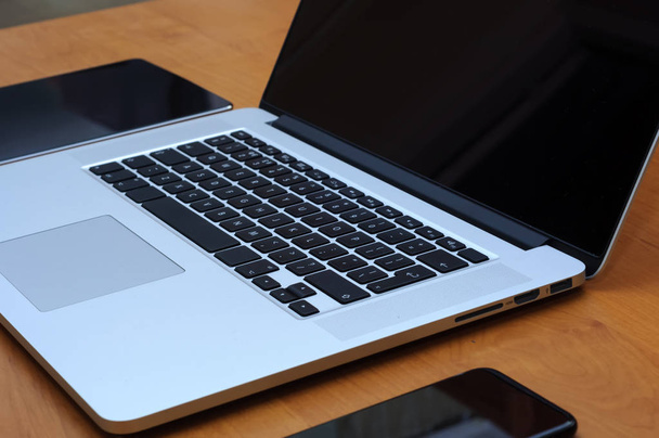 Bekijk op een laptop pc en een smartphone en een tablet op een bureau in een thuiskantooromgeving in de woonkamer. - Foto, afbeelding