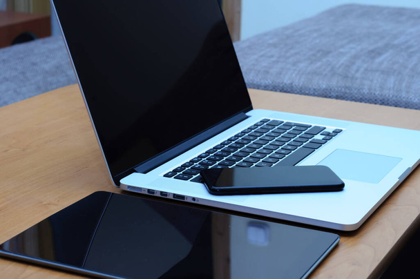 Näkymä kannettava tietokone ja älypuhelin ja tabletti työpöydällä kotitoimiston ympäristössä olohuoneessa
. - Valokuva, kuva