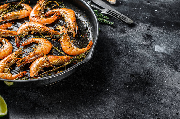 Grilled giant prawns, shrimps with garlic, lemon, spices in pan. Black background. Top view. Copy space. - Foto, Imagen