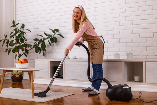 Домохозяйка чистит свой дом с помощью вакуума
. - Фото, изображение