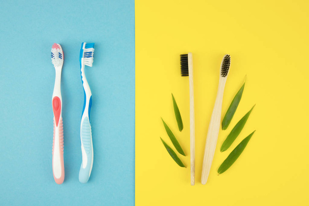 Két műanyag fogkefe és két bambusz fogkefe bambuszlevelekkel, kék és sárga alapon. Természetes anyagok a mindennapi életben. Szájápolás - Fotó, kép