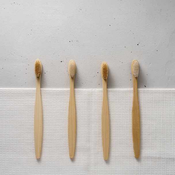 Verschillende bamboe tandenborstels op een lichte betonnen ondergrond. Bovenaanzicht met kopieerruimte. - Foto, afbeelding