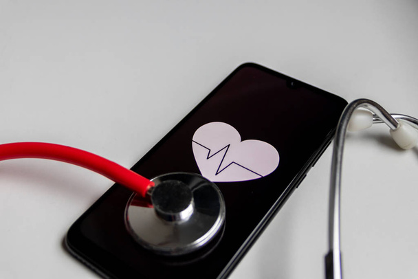 Estetoscopio y teléfono inteligente negro con un símbolo del corazón y latidos del corazón para mostrar la oficina de médicos digitales, diagnóstico digital y rastreador de salud, así como estadísticas de salud y medicamentos asistentes de salud
 - Foto, imagen