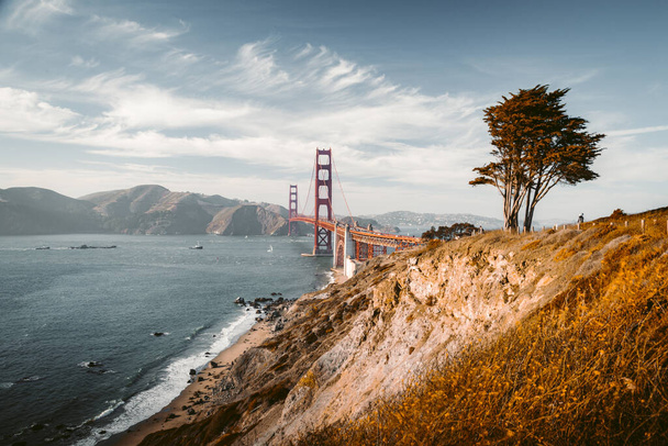 Klassiek uitzicht op de beroemde Golden Gate Bridge in het prachtige gouden avondlicht op een zonnige dag met blauwe lucht en wolken in de zomer, San Francisco, Californië, Verenigde Staten - Foto, afbeelding