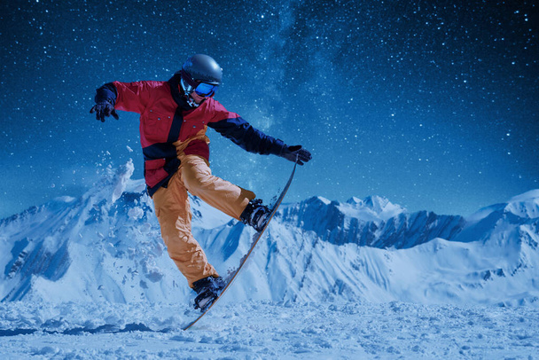 yöluistelu Lumilautailija kirkkaissa urheiluvaatteissa tekemässä tasapainotemppua kauniita vuoria vastaan tähtitaivaan ja kuunvalon alla
 - Valokuva, kuva