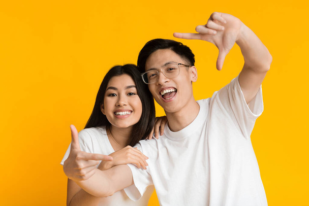 Молодой азиат мужчина и женщина показывают рамку знак с руками
 - Фото, изображение