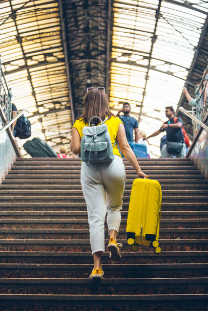 жінка з жовтим мішком піднімається сходами на залізничній станції концепція подорожі
 - Фото, зображення