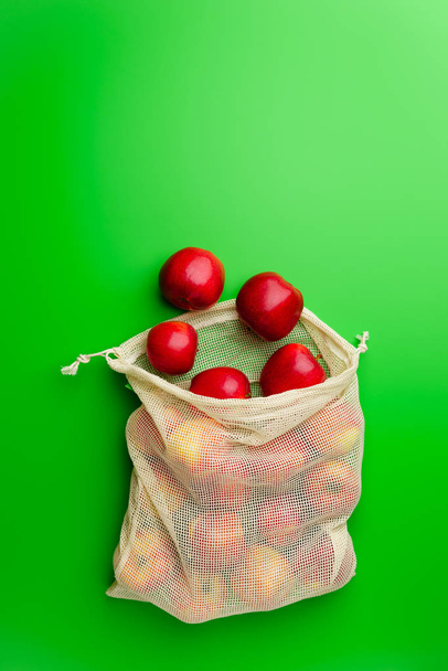 Ruokakauppa puuvilla net laukku punaiset omenat vihreällä pohjalla. Tasainen lay, kopioi tilaa
. - Valokuva, kuva