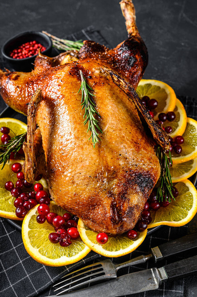 Baked goose stuffed with oranges and rosmarina. Festive table. Black background. Top view - 写真・画像