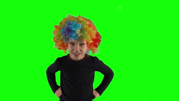 Fille en colère avec perruque clown coloré regardant la caméra. Émotion négative de l'enfant - Séquence, vidéo