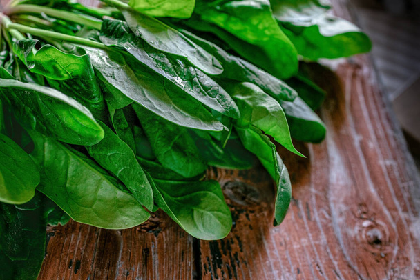A bunch of young fresh juicy green spinach on a rustic wooden old-time red background. Flat lay. Copy space - Fotó, kép