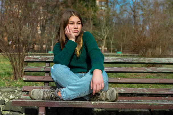грустная девочка-подросток сидит в парке
 - Фото, изображение