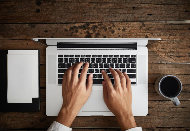 A man is typing on laptop keyboard on modern white office desk, top vie - Фото, зображення