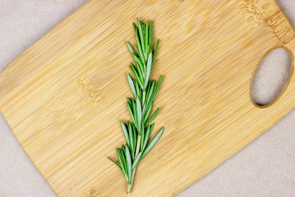 Vue de dessus des branches, brindilles et feuilles de romarin vert vif sur une planche de bois sur fond clair
. - Photo, image