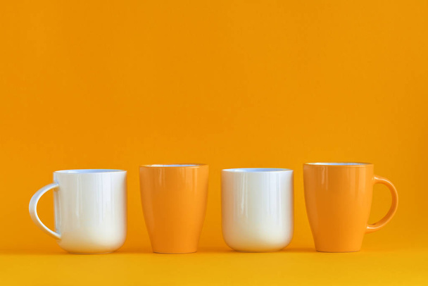White and yellow coffee cups aligned on yellow background with copy space - Foto, Bild