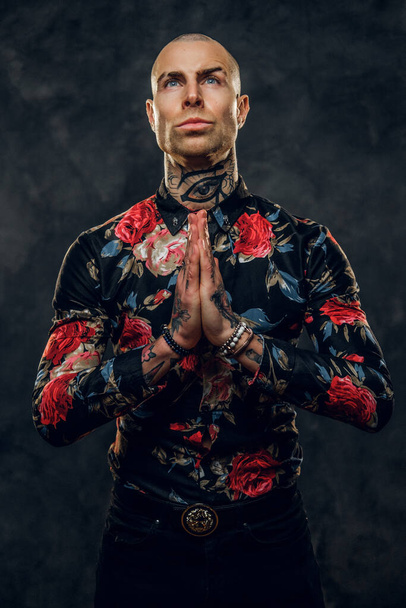 Elegante modelo masculino tatuado y calvo de moda posando en un estudio para el estilo de moda de la sesión de fotos mostrando un gesto de oración
 - Foto, Imagen