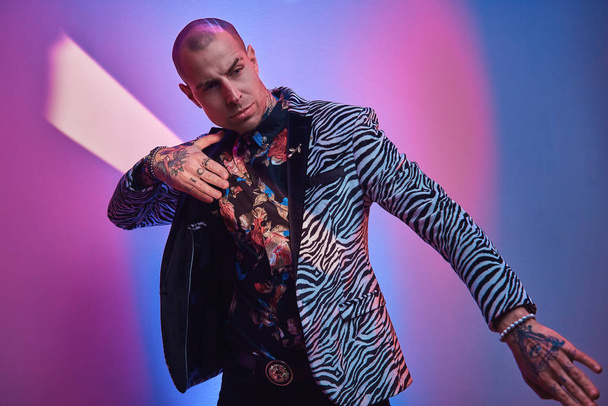Горячие татуированные, лысый модный мужчина модель позирует в студии для фотосессии моды стиль показывая жест с руками
 - Фото, изображение