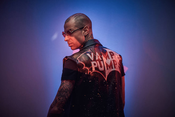 Brutal tatuado, careca modelo masculino elegante posando em um estúdio para o estilo vogue photoshoot, olhando por trás
 - Foto, Imagem