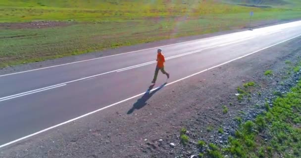 Low altitude flight in front of sporty man at perfect asphalt road - Footage, Video