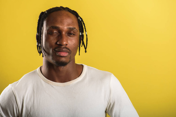 portrait of a young black man, african appearance, emotional and serious and looking upwards, flailing his hands, from dreadlocks, against yellow background  - Foto, Imagem