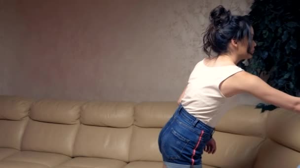 beautiful brunette girl puts on a shirt at home in the living room.  lifestyle - Кадры, видео