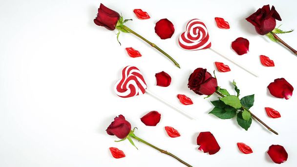 Red roses, petals, lollipops and chocolates creative composition layout. - Fotó, kép