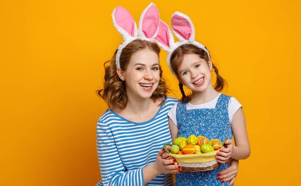 Joyeux Pâques ! mère de famille et fille enfant avec des oreilles lièvre se préparer pour les vacances sur fond jaune coloré
 - Photo, image