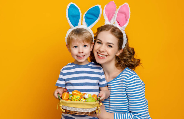 Joyeux Pâques ! mère de famille et enfant fils avec des oreilles lièvre se préparer pour les vacances sur fond jaune coloré
 - Photo, image