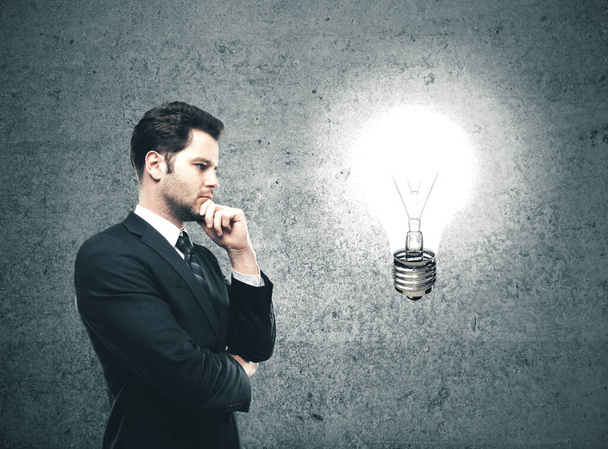 Businessman looking on glowing lamp Success and startup concept. - Фото, изображение