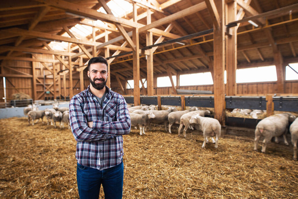 Pracownik farmy Cattleman z dumą stoi na farmie z skrzyżowanymi rękami.. - Zdjęcie, obraz
