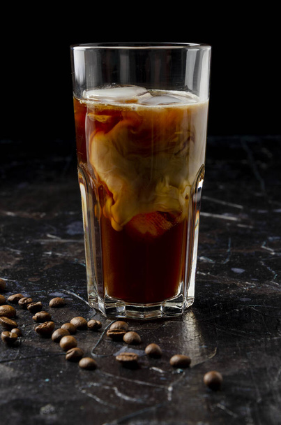 Iced coffee in a glass with pouring milk in black - Foto, immagini