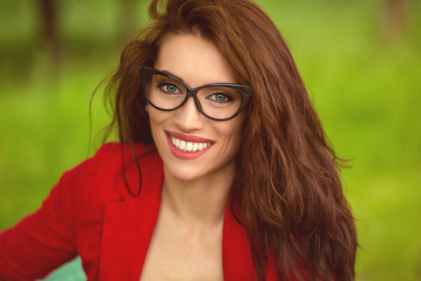 Sorridente. Ritratto di giovane donna, felice ragazza bruna con gli occhiali, all'aperto nel parco. Espressione facciale positiva
. - Foto, immagini