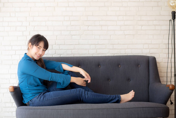 Bella ritratto giovane donna asiatica seduta e sorridente felice e guardando la fotocamera sul divano con casual in soggiorno, ragazza allegra e rilassarsi sul divano a casa, concetto di stile di vita
. - Foto, immagini