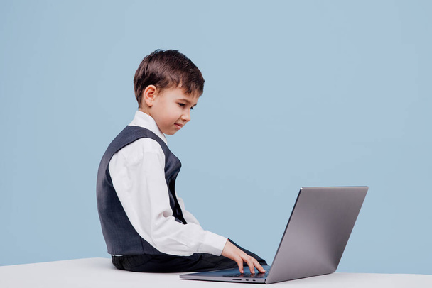 Focused small boy using laptop in studio - Foto, imagen
