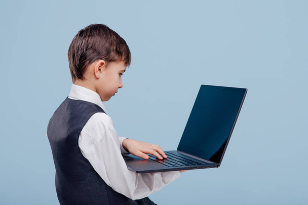 back view little schoolboy typing on laptop - Фото, зображення
