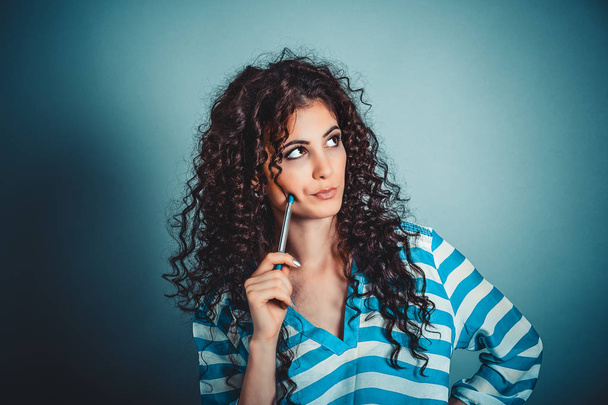 Think. Portrait close up of beautiful curly young woman thinking looking away, up isolated blue wall background with copy space. Human face expressions, emotions body language, attitude perception  - Foto, Imagem