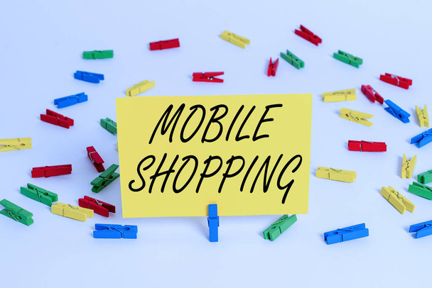 Handwriting text Mobile Shopping. Concept meaning trading of goods and services through wireless devices Colored clothespin papers empty reminder white floor background office. - Foto, Bild
