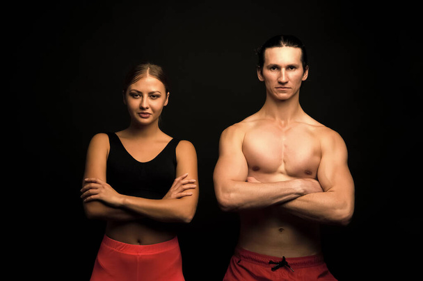 Sports for all. Sexy fit couple black background. Professional sports team. Athletic man and woman keep muscular arms crossed. Taking sports to stay in shape. Physical training and sports - Fotografie, Obrázek