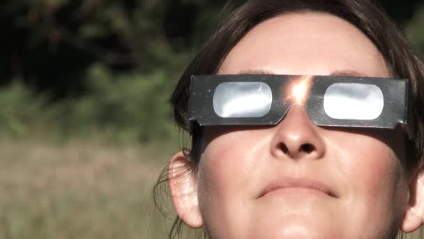 保護眼鏡をかけたモデルリリース女性は日食を見ながら反応します. - 映像、動画