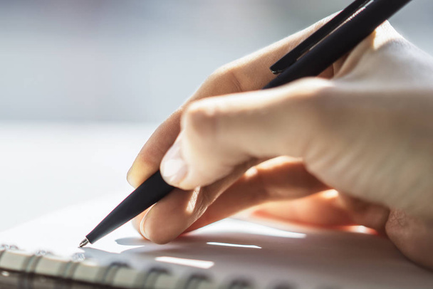 Женщина пишет с ручкой в блокноте в солнечном офисе, бизнес и образовательной концепции. Закрыть
 - Фото, изображение